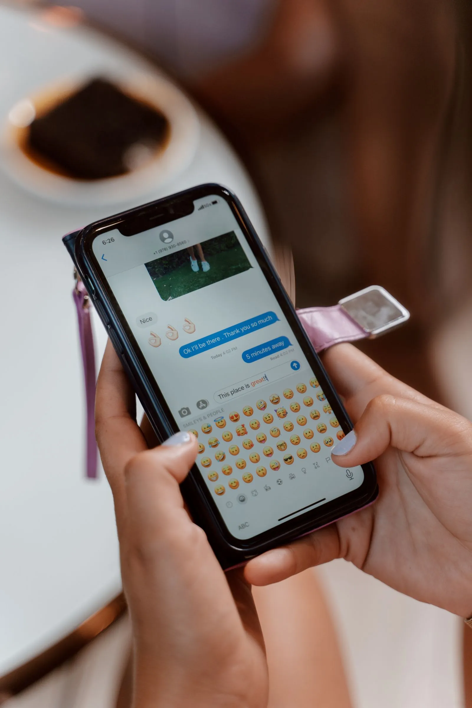 Hand holding a phone showing a text message conversation with a returning client